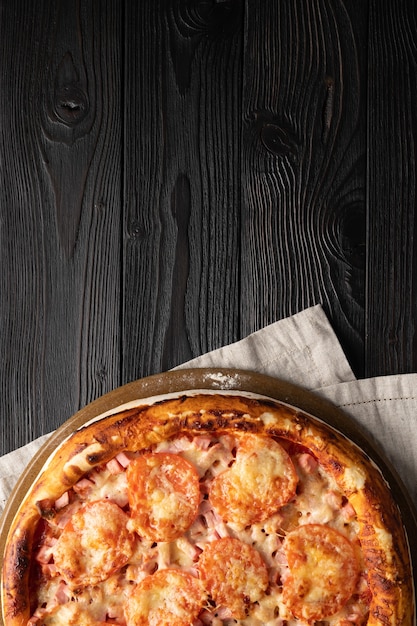 Cooked pizza on a wooden background, place for text, top view