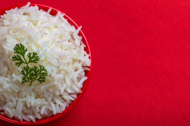Фото Приготовленный простой белый рис басмати в красной миске на красном