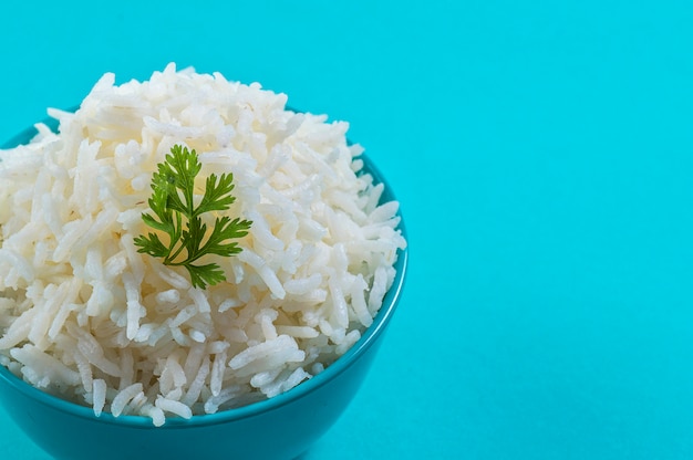 Riso basmati bianco normale cotto con il coriandolo in una ciotola blu