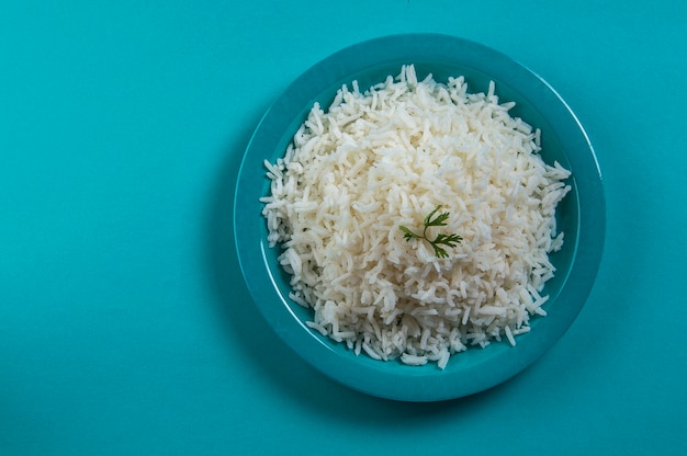 Cooked plain white basmati rice with corriander in a blue plate on blue