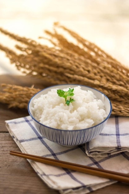 Приготовленный рис в миске с палочками на деревянном фоне.