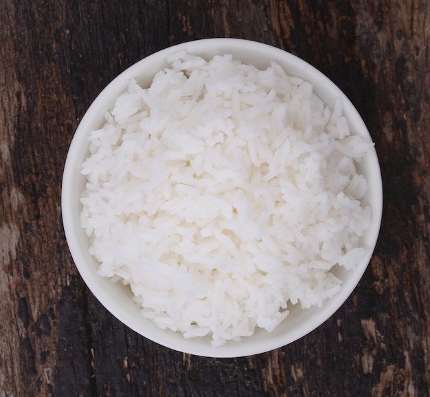 Cooked rice in bowl on wood background.