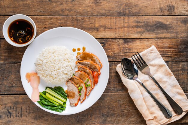 Cooked rice with roasted duck on white plate and old wooden desk traditional Thai food.