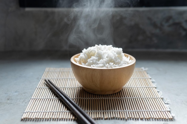 Фото Приготовленный рис с паром в черной миске на темном фоне, горячий приготовленный рис в миске с избирательным фокусом, горячая еда и здоровая