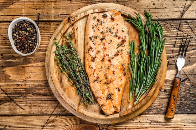 Filetto di salmone cotto alle erbe e pepe rosa. fondo in legno. vista dall'alto.