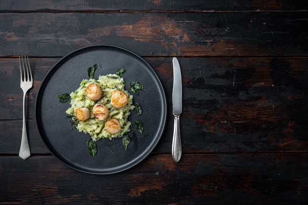 Capesante cotte con purè di patate alla menta e piselli, piatto, su fondo di legno scuro con spazio per il testo