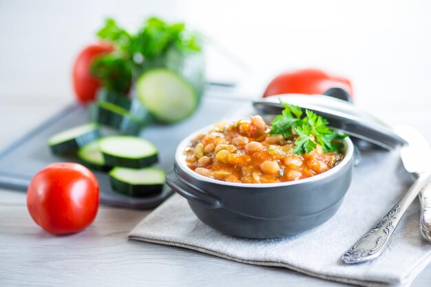 Cooked white beans with zucchini and other vegetables on a wooden table