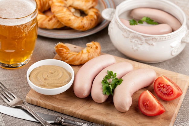 Cooked white sausages with beer and pretzel