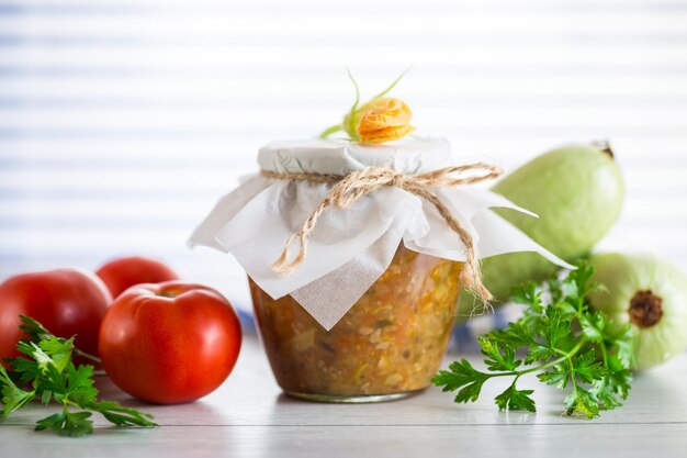 Cooked zucchini caviar with tomatoes in a glass jar preservation