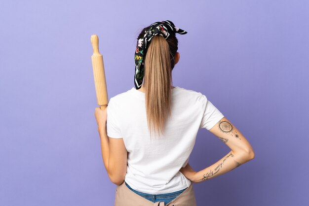 Cooker slovak woman isolated on purple wall in back position