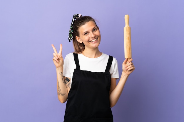 Cooker Slovak woman isolated on purple wall smiling and showing victory sign