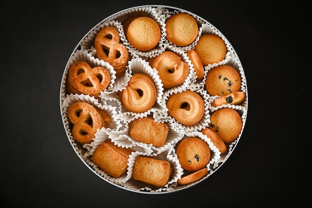 Cookie box with danish butter cookies on black table background top view