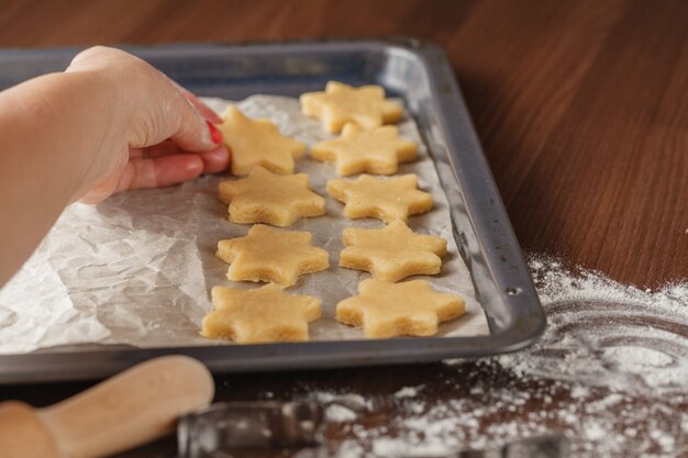 Cookie cutters and shortbread shapes on a board and a baking tray