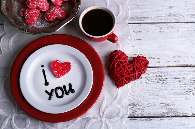 Cookie in form of heart on plate with inscription I Love You on color wooden table background