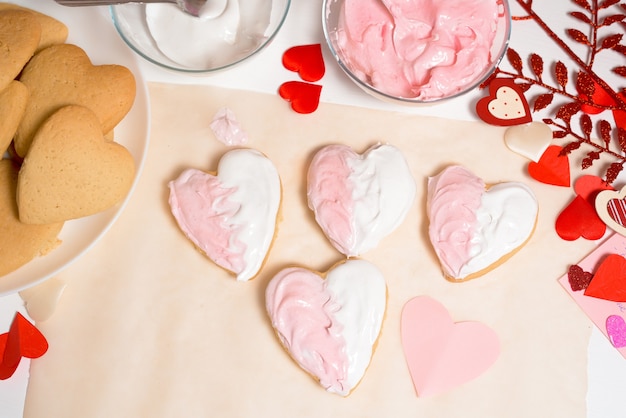 Cuore di biscotto decorato con smalto bianco e rosa per il giorno di san valentino, primo piano, cottura per le vacanze. vista dall'alto di cuori decorativi.