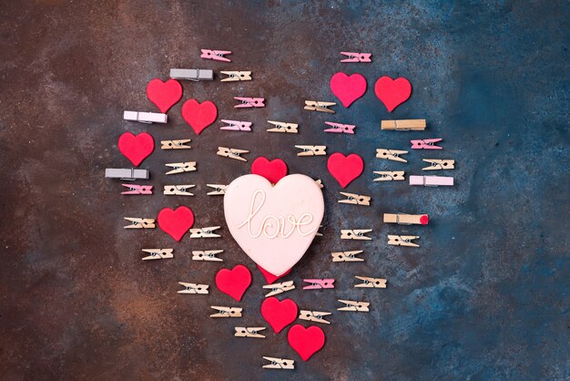 Cookie heart with a glaze, red hearts and clothespins made on stone background, flat lay.