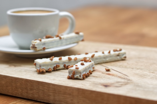 Cookie wafers in glaze and cup of coffee on a wooden table