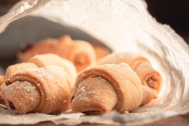 Cookies bagels with jam in powdered sugar in a plate on a dark background.