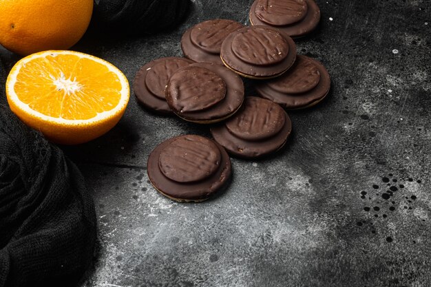 Cookies covered with chocolate and filled with jam set, on black dark stone table background, with copy space for text