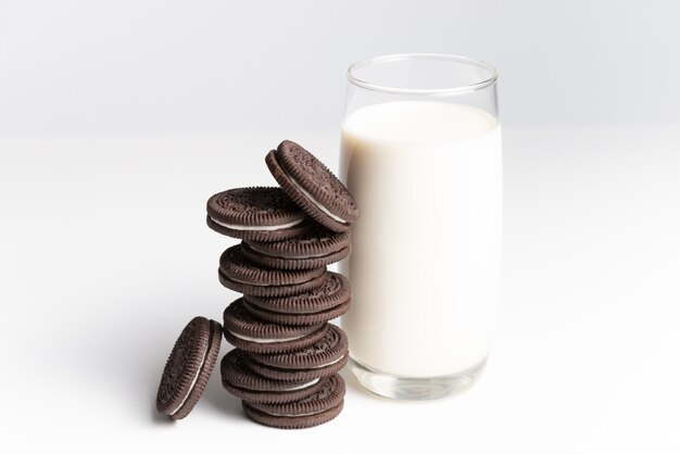 Cookies and cream of chocolate flavour in stack with glass of fresh milk on white backgrou