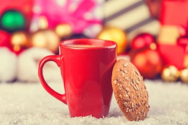 Cookies and cup of coffee with christmas gifts at background