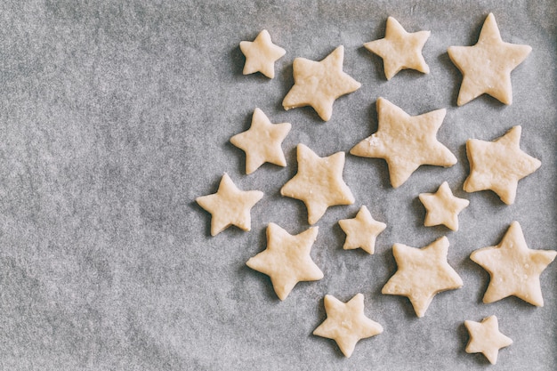 Photo cookies in the form of stars on parchment paper lies in baking tray, holiday pastries, christmas cookies