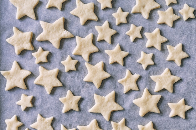 Foto i biscotti a forma di stelle su carta pergamena si trovano nella teglia