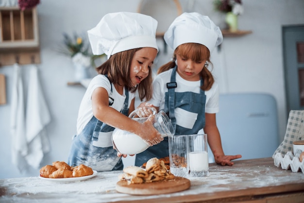 Cookies is ready. Family kids in white chef uniform preparing food on the kitchen.