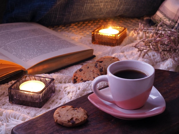 Cookies kopje thee of koffie gebreide deken boek en brandende kaarsen