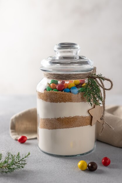 Cookies mix with color candies in a glass jar