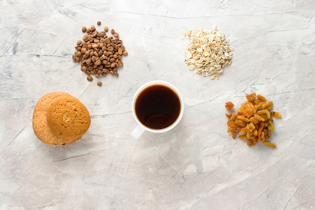 Cookies, Oatmeal, Coffee, Raisins and a cup of coffee on a light background. Breakfast Concept