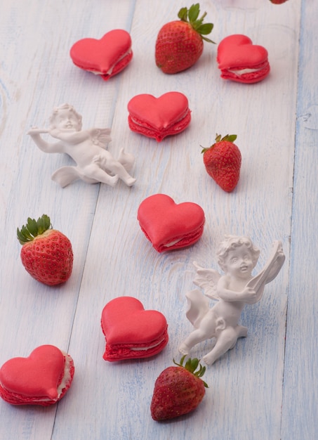 Cookies red heart shaped strawberries and angel on the wooden boards on Valentines Day