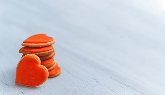 Cookies in the shape of hearts piled in a stack on a light wooden table