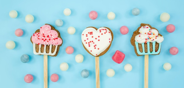 Cookies on  stick and candy on blue background Delicious sweets top view copy space cake sweet heart