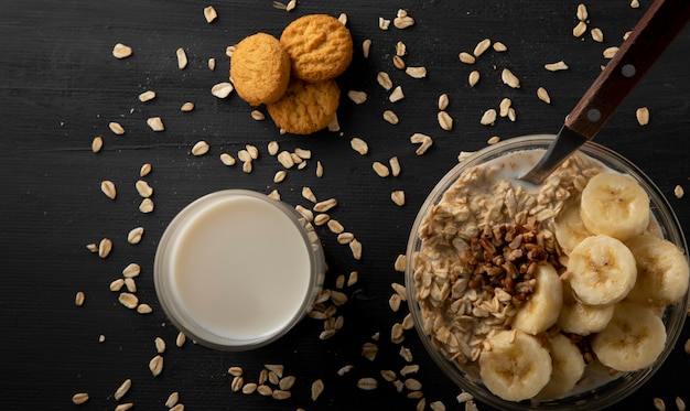 Cookies on a table with oatmeal and a glass of milk next to it dark food concept