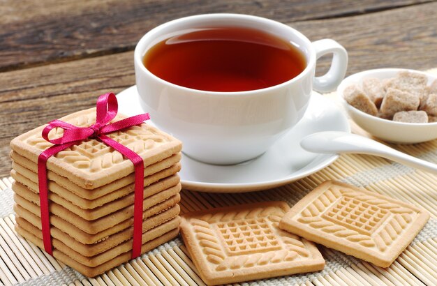 Cookies tied red ribbon and cup of tea on wooden table