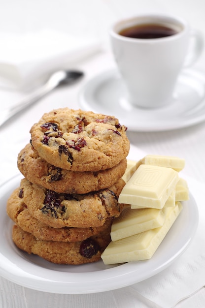 Cookies, white chocolate and cup of coffee on table