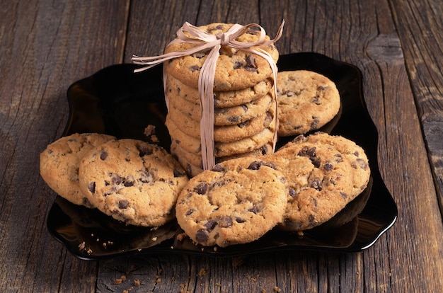 Cookies with chocolate in black plate on old wooden table