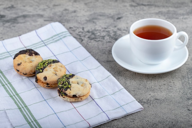 Cookies with chocolate and cup of black tea on stone background. 