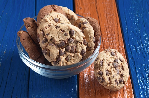 Cookies with chocolate and nuts in glass bowl on colorful table