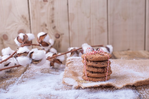 木製のテーブルと雪の上の赤いロープで縛られてチョコレートクッキー