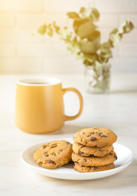 Cookies with chocolate on white plate and tea on table