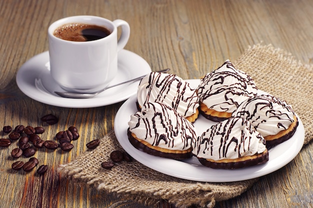 Cookies with cream chocolate and coffee cup on old wooden table