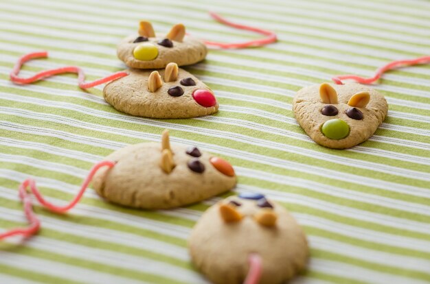 Cookies with mouse shaped and red licorice tail over green striped tablecloth