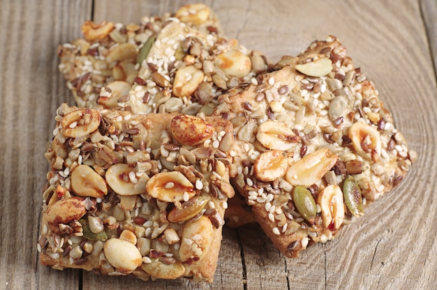 Cookies with nuts, sesame and sunflower seeds on old wooden table. Macro photo