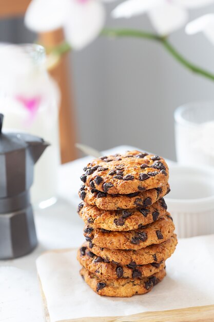 Cookies with pieces of chocolate are laid out on a wooden board with a white napkin