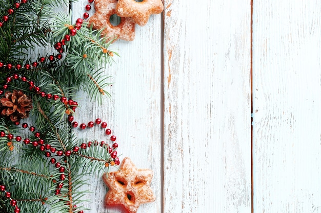 Cookies with sprig of Christmas tree on color wooden background