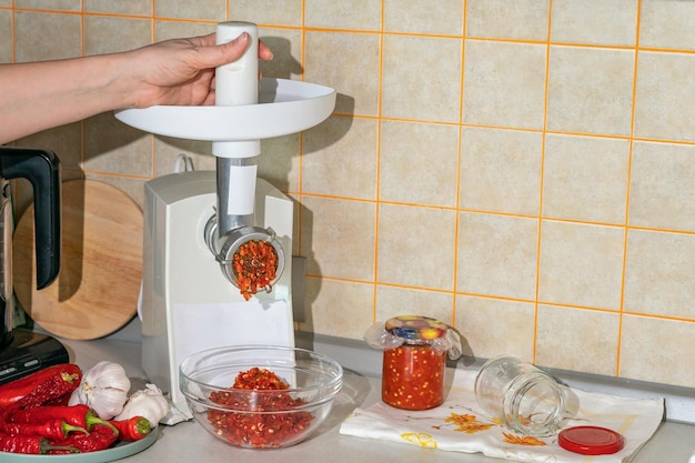 Photo cooking adjika from hot pepper and garlic ground in a meat grinder preparations for the winter