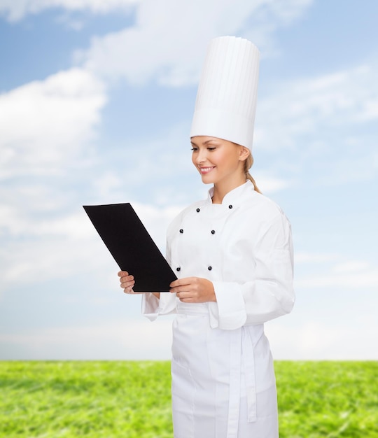 cooking, advertisement and food concept - smiling female chef with blank black paper