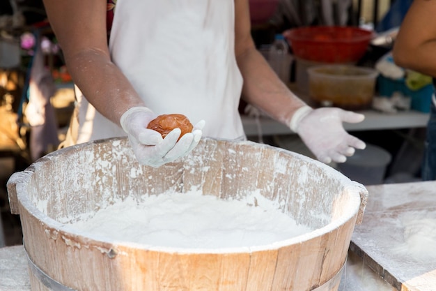 cooking, asian kitchen, sale and food concept - close up of cook hands with meatball and flour at street market